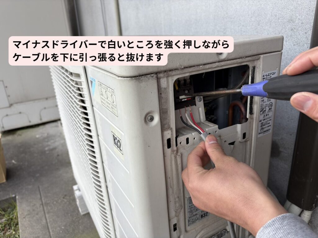 室外機の電線をマイナスドライバーを使って抜く様子